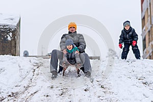 Family sledding. Little boy and mother sliding in the park.