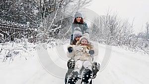 family sledding in winter. outdoor winter activity. Happy, laughing family, woman with 2 daughters are enjoying of