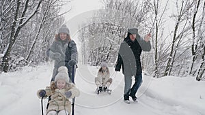 family sledding in winter. outdoor winter activity. Happy, laughing, playful family of 4 is enjoying of sledging their