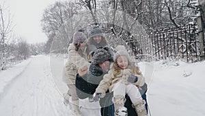 family sledding in winter. outdoor winter activity. Happy, laughing, playful family of 4 is enjoying of sledging their