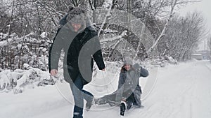 family sledding in winter. outdoor winter activity. Happy, laughing, playful married couple is enjoying of sledging on