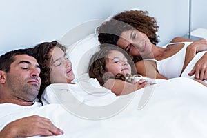 Family sleeping together on bed