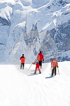 Family on slope. Rocky mountains in background.