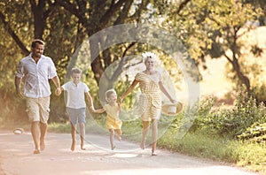 A family with small children running barefoot on a road in summer.