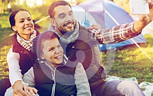 Family with smartphone taking selfie at campsite