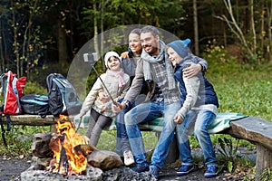 Family with smartphone taking selfie near campfire