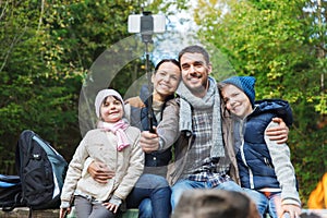 Family with smartphone taking selfie near campfire