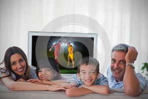 Family smiling at the camera with world cup showing on television