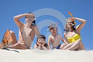 Family with snorkeling masks sitting on sa