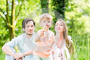 Family with son on meadow blowing dandelion seed