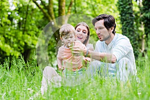 Family with son on meadow blowing dandelion seed