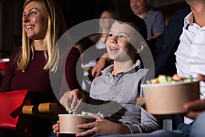 Family with son watching movie and eating popcorn in cinema