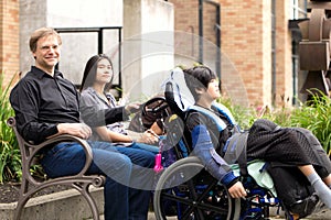 Family with special needs child sitting outdoors together in sum