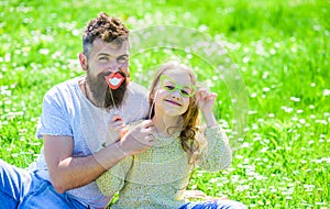 Family spend leisure outdoors. Dad and daughter sits on grass at grassplot, green background. Child and father posing