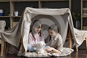 Family spend playtime on floor under handmade wigwam