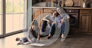 Family spend time at home sitting on floor in kitchen