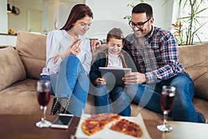 Family spending time at home and looking something fanny on tablet