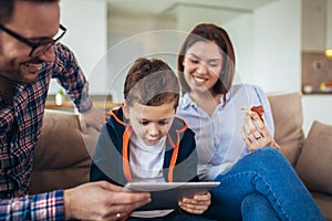 Family spending time at home and looking something fanny on tablet