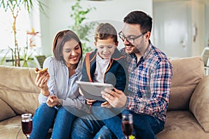 Family spending time at home and looking something fanny on tablet