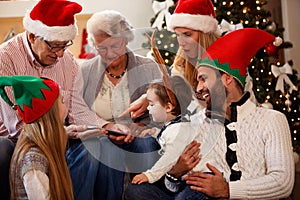 family is spending time together on Christmas day and using tablet.