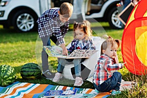 Family spending time together. Girl reading book outdoor with brother and sister