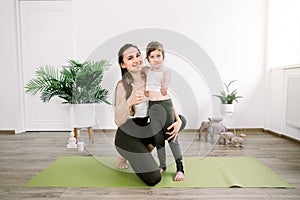 Family sport and yoga concept. Promotion of healthy lifestyle. Mother and little daughter smiling together at camera and