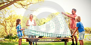 Family spreading the tablecloth on picnic table
