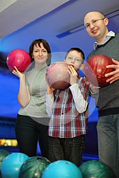 Family stand alongside and hold balls for bowling photo