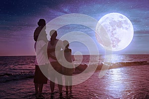 Family standing on beach and watching the moon.Celebrate Mid-autumn festival