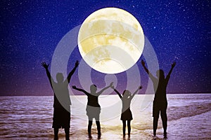 Family standing on beach and watching the moon.Celebrate Mid autumn festival