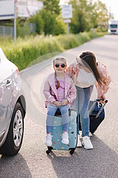 Family standing by the car with suitcases and waiting journey. Mom and daughter preparing for trip.