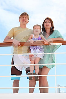 Family standing on cruise liner deck near rail