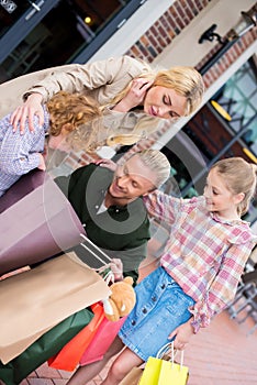 Family standing and looking into shopping bags on street