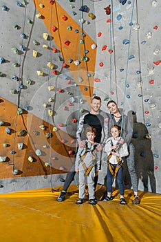 Family with children standing together near climbing walls at gym and looking