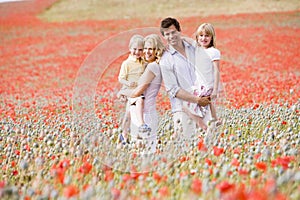 Family standing in poppy field smiling