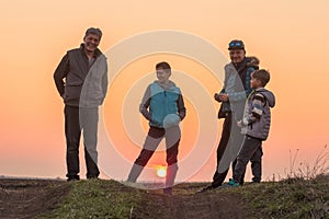 A family stands against a picturesque sunset