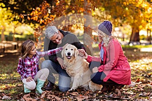 Family stroking dog while crouching at park