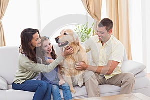 Family stroking dog while sitting on sofa