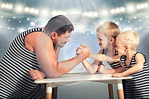 Family of strongman. The father of two sons in vintage costume of athletes compete in arm wrestling. Family look.