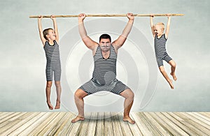 Family of strongman. Father and two sons in vintage costumes drag the rope. Family look.