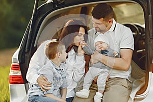 Family in a summer forest by the open trunk