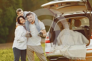 Family in a summer forest by the open trunk