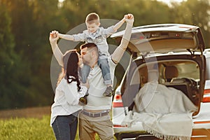 Family in a summer forest by the open trunk