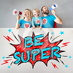 Family of superheroes holding banner