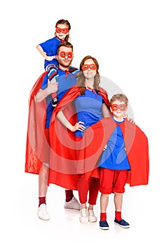 family of superheroes in masks and cloaks smiling at camera