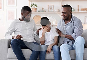 Family Support. Black father and grandfather comforting upset little boy at home