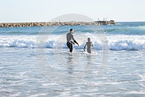 A family of surfers - father and son in wetsuits go to sea