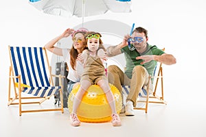 Family in swimming goggles depicting swim with sunshade, sun loungers and ball