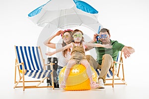 Family in swimming goggles with sunshade sun loungers and ball