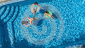 Family in swimming pool aerial drone view from above, happy mother and kids swim on inflatable ring donuts and have fun in water